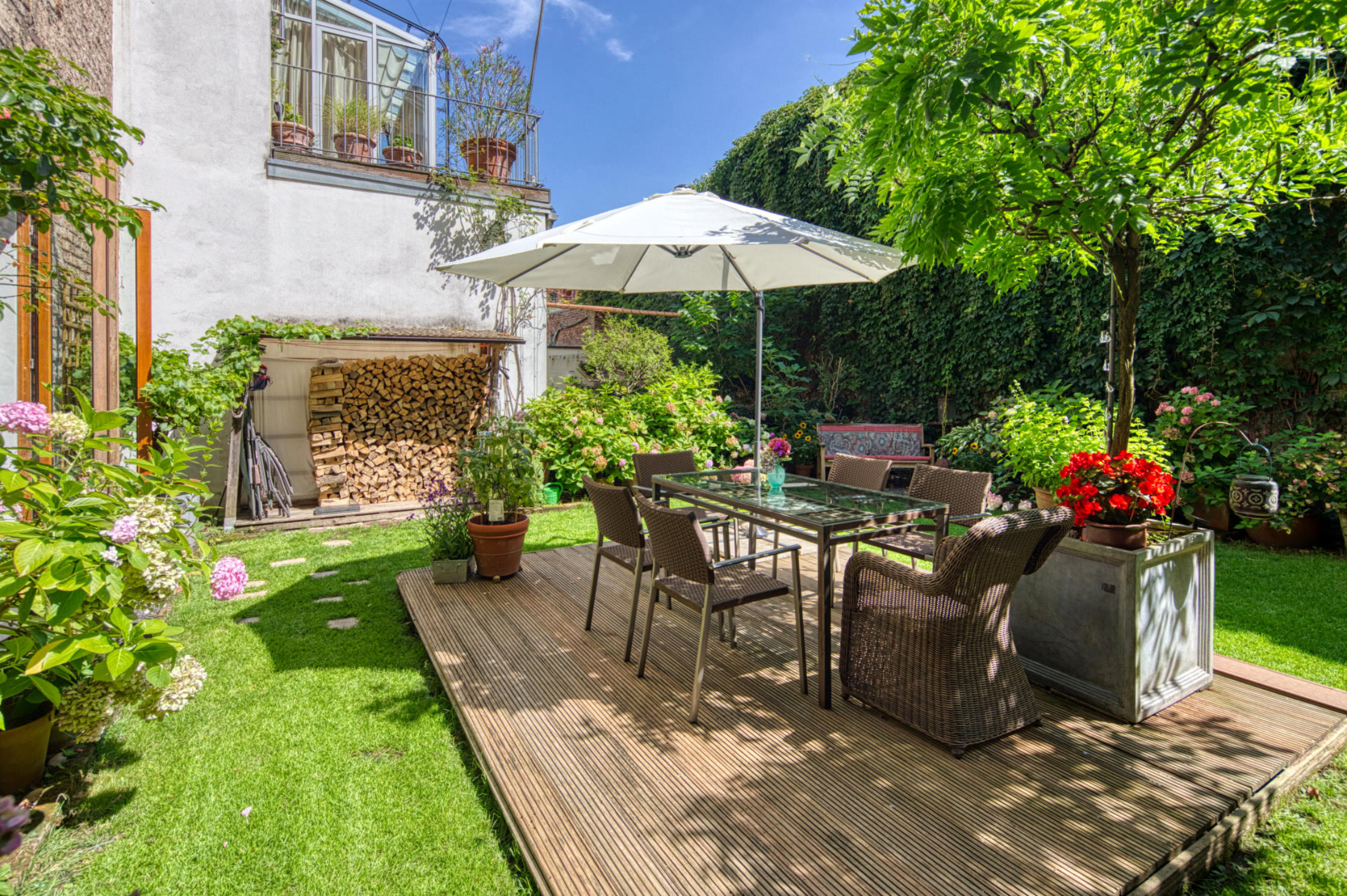 Sonnige Gartenterrasse mit Sonnenschirm und Essplatz einer Immobilie im Rheinland